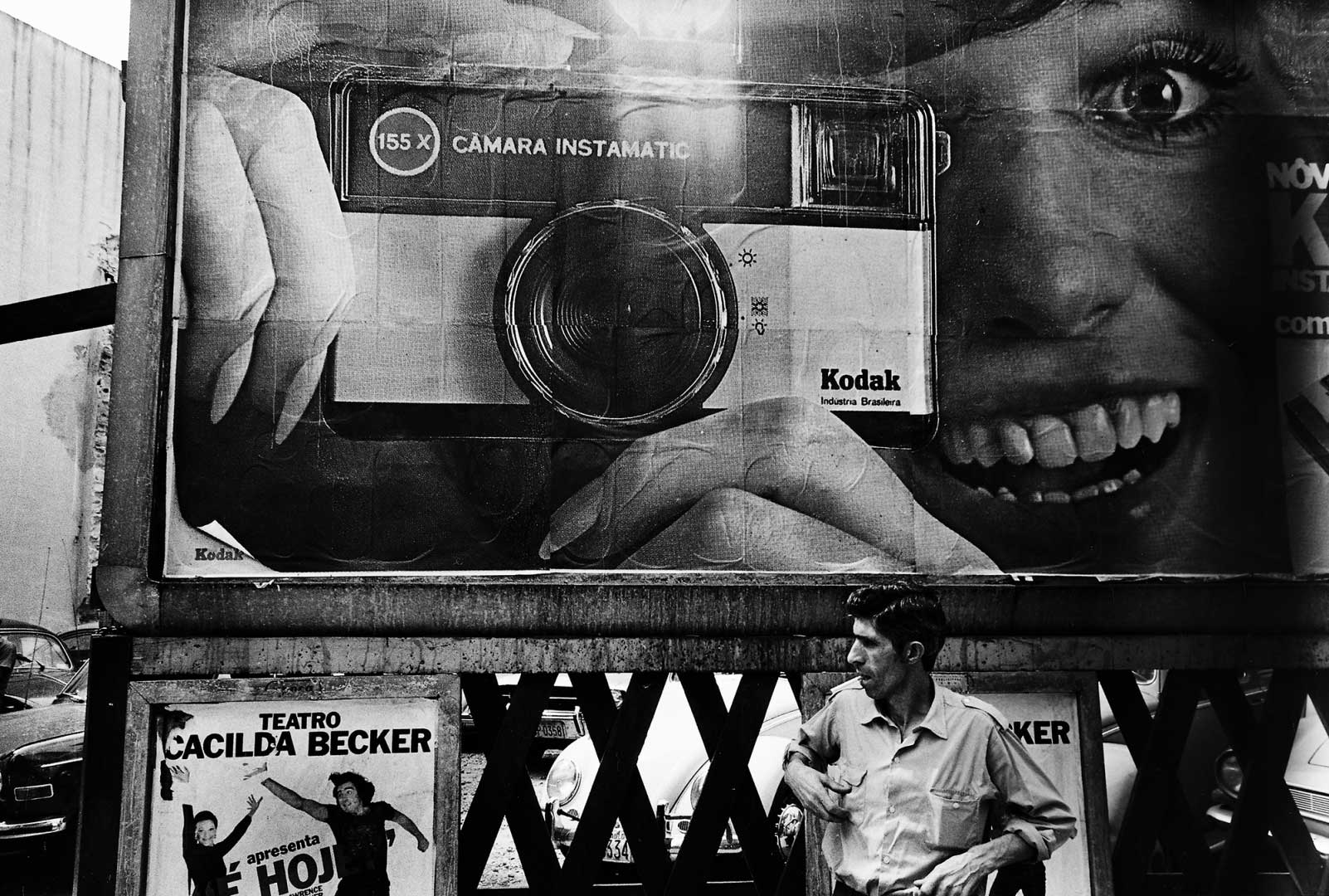 uomo davanti a cartellone pubblicitario con donna che scatta fotografia