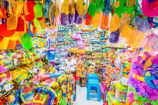 ragazza seduta in negozio pieno di oggetti di plastica colorati