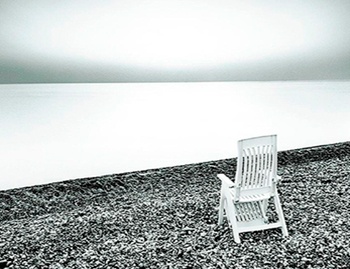 foto in bianco e nero di una sedia al mare