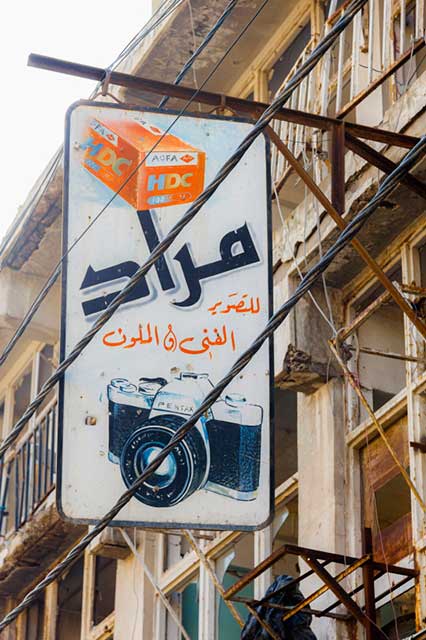 insegna con disegno di rullino agfa e di macchina fotografica pentax e scritte in arabo
