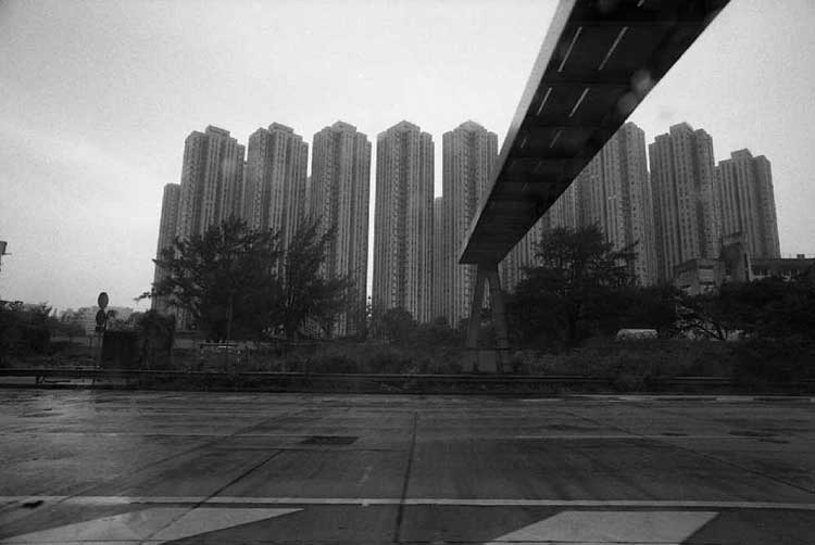 fotografia in bianco e nero di una strada con ponte e sullo sfondo grattacieli