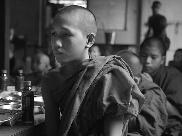 fotografia in bianco e nero di un ragazzo con la testa rasata e lo sguardo triste