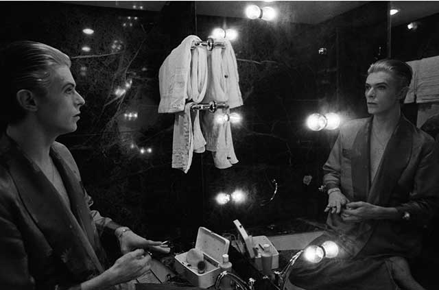 fotografia in bianco e nero di david bowie in camerino che si guarda nello specchio