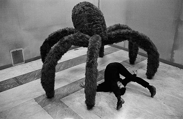 uomo sdraiato sotto scultura gigante di ragno
