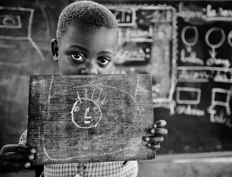 fotografia in bianco e nero di un bambino che tiene in mano una tavolozza con un disegno