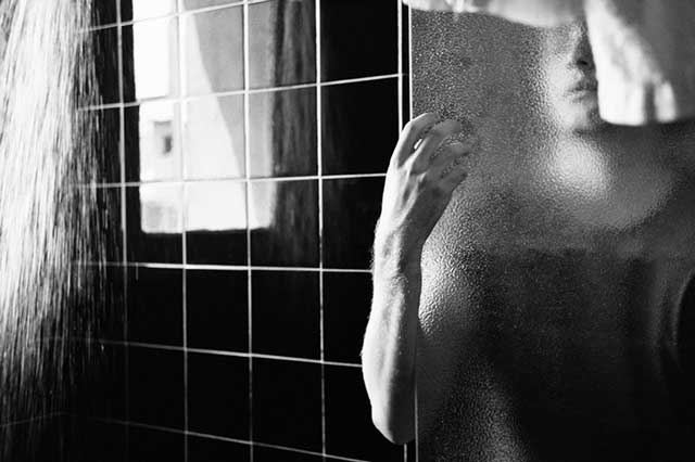 fotografia in bianco e nero di un Uomo in bagno dietro vetro appannato appannat