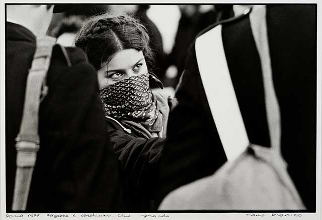 fotografia in bianco e nero di una ragazza con bandana che le copre il volto fra i carabinieri
