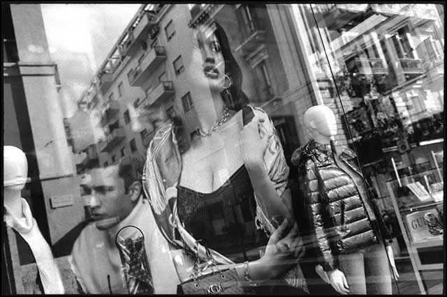 donna riflessa nella vetrina di un negozio di abbigliamento