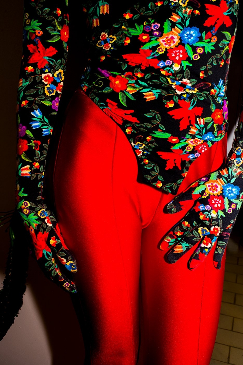 dettaglio di gambe di donna con pantaloni rossi e body e con guanti a fiori