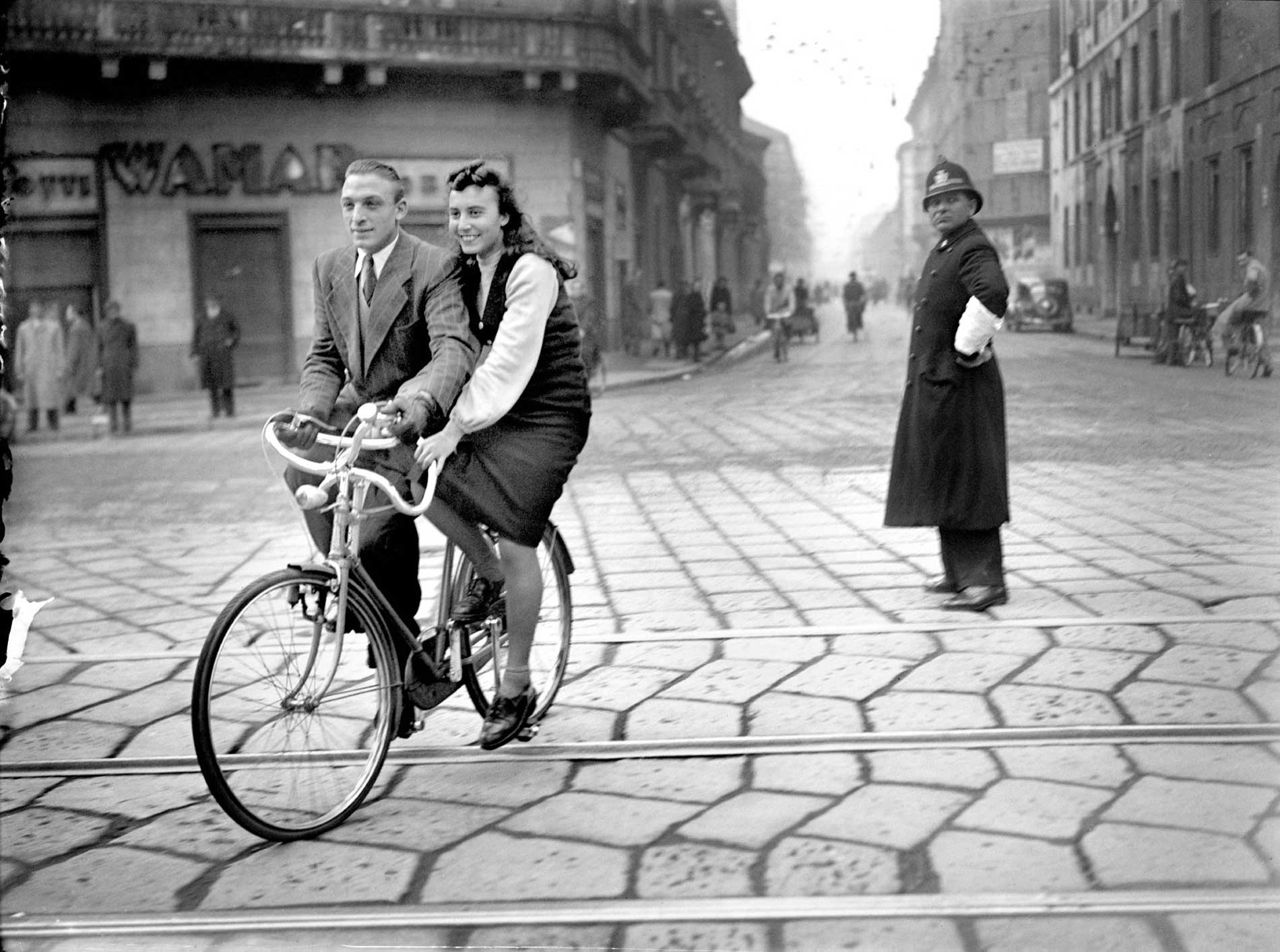 ragazzi in bicicletta con dietro vigile che li guarda