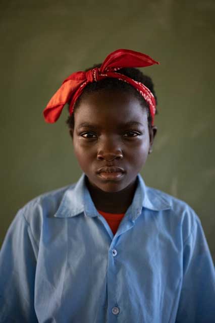 primo piano di bambina africana con camicia celeste e fazzoletto rosso in testa