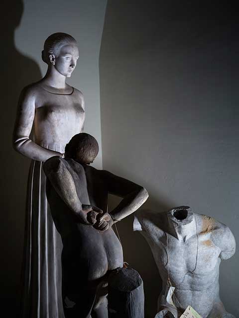 tre statue,una donna in piedi,un uomo inginocchiato e un busto senza testa