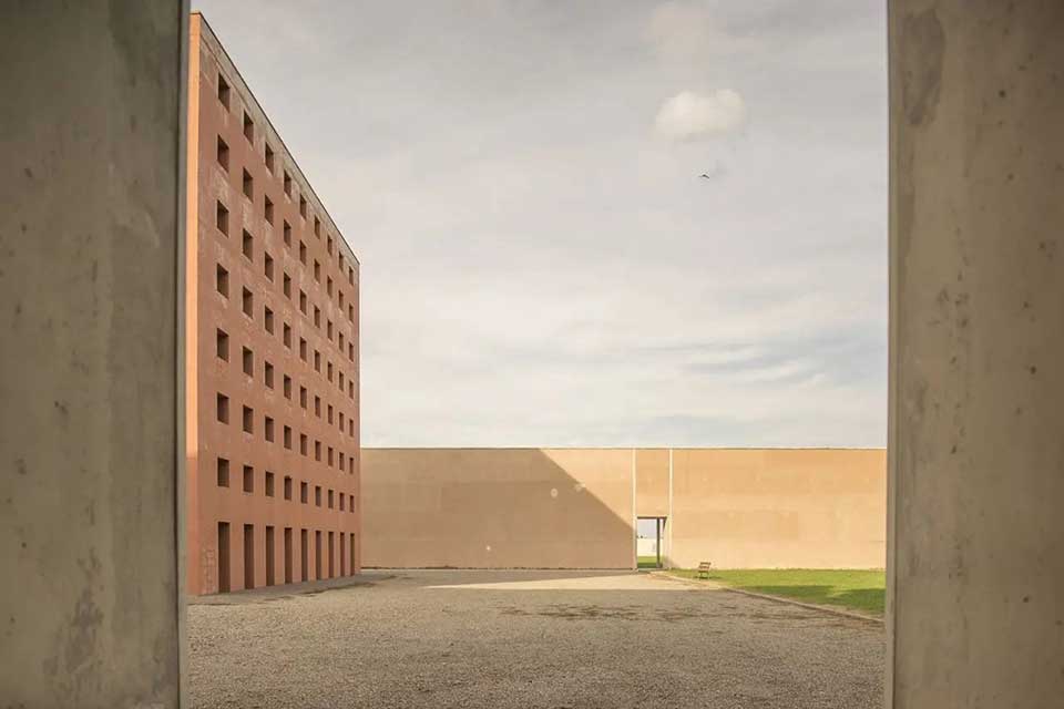 cortile deserto con palazzo senza finestre e muro di cinta