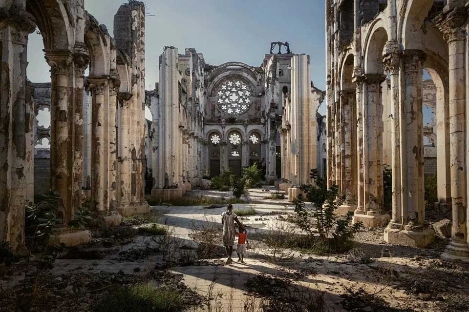 donna e bambino che camminano all'interno di una cattedrale distrutta