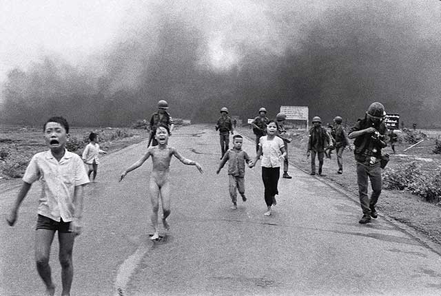 gruppo di bambini e soldati che scappano su una strada allo scoppio di una bomba al napal in Vietnam che