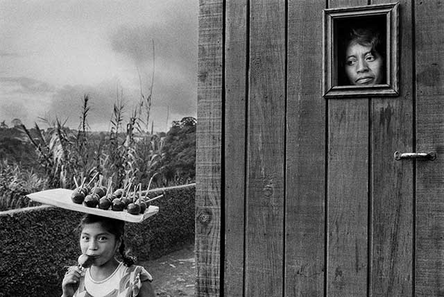 donna che guarda dalla finestra bambina con vassoio pieno di mele caramellate in testa