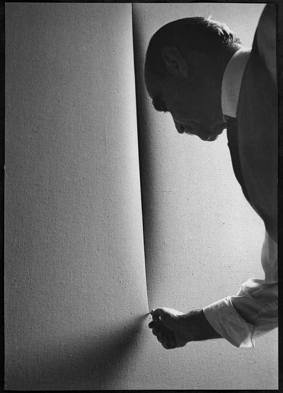 Lucio Fontana che taglia una tela