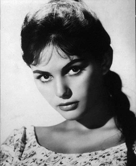 primo piano di Claudia Cardinale giovane con capelli legati con treccia e vestito a fiorellini bianco