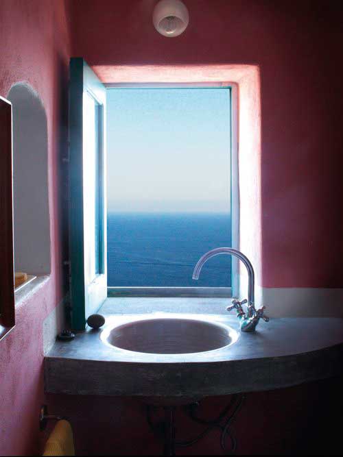 bagno con pareti rosa e lavandino sotto finestra aperta sul mare