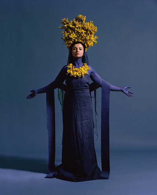donna dipinta e vestita di blu con in testa e al collo delle mimose