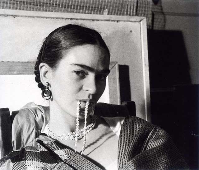 ritratto di Frida Kahlo con capelli raccolti e collana di perle in bocca