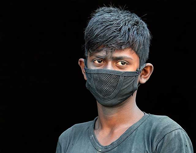 primo piano di ragazzo indiano pensieroso con mascherina nera sul volto