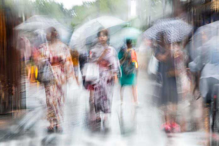 foto mossa di donne giapponesi che camminano per strada con l'ombrello