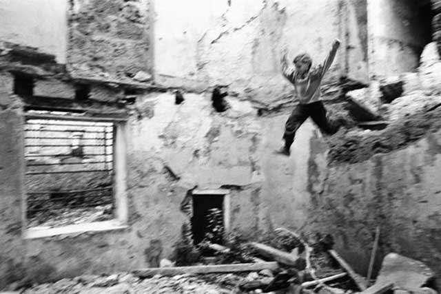 bambino che salta da un muro di palazzo distrutto e abbandonato
