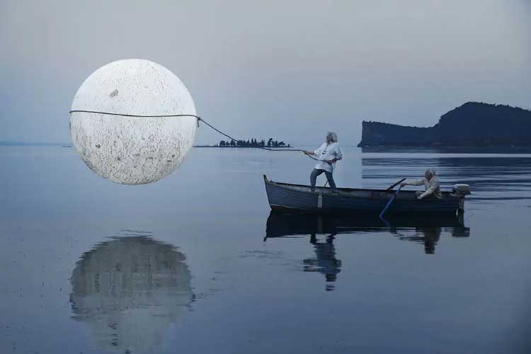 Valentina Vannicola uomo in barca sul lago che tiene la luna al guinzaglio