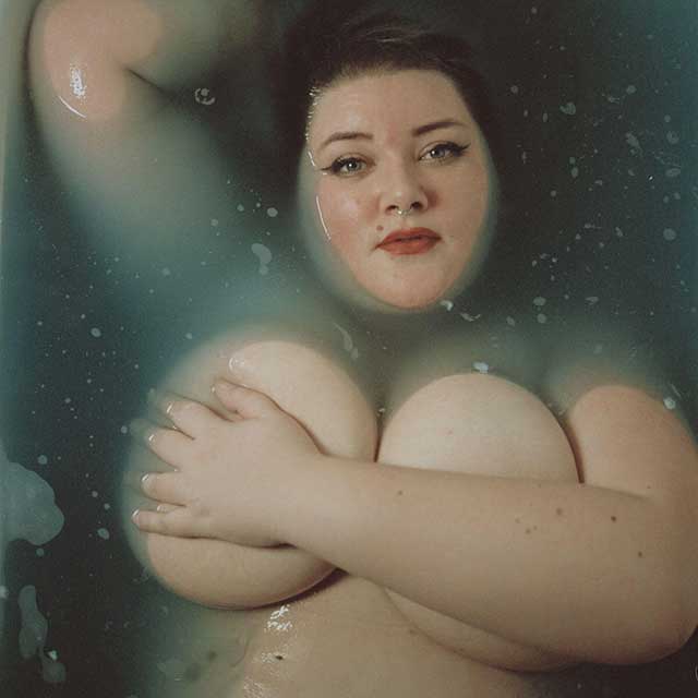 donna vista dall'alto molto prosperosa nuda con un braccio sul seno immersa nell'acqua in una vasca