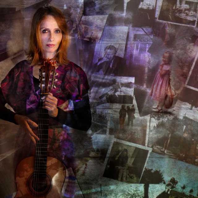 donna con in mano una chitarra davanti a pannello pieno di fotografie