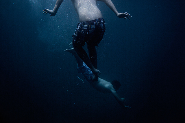 due ragazzi che nuotano sott'acqua in un mare blu intenso