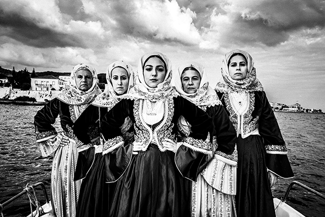 Sony World Photography Awards foto in bianco e nero con 5 donne con vestiti folkroristici e fazzoletti in testa con le mani sui fianchi e lo sguardo fiero in piedi su una barca