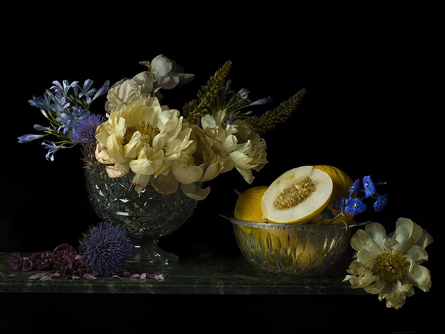 marcello bonfanti foto di natura morta composta da vaso con fiori gialli e lilla e coppa con frutto giallo aperto e fiori gialli e viola appoggiati su piano di marmo