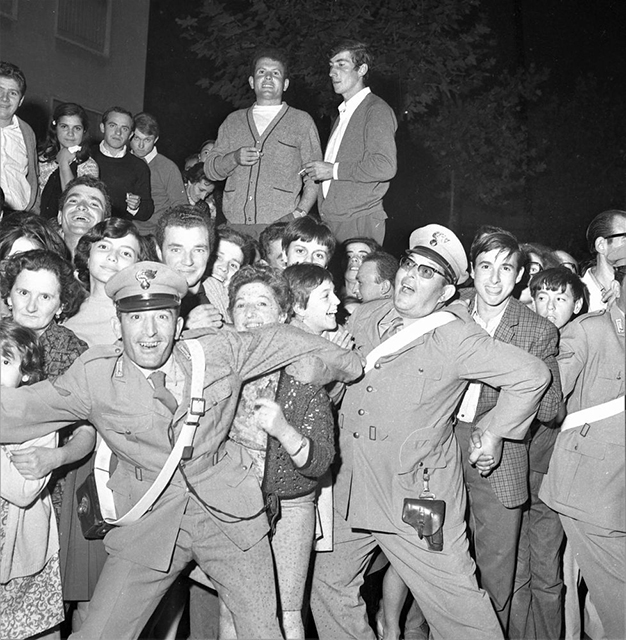 prospero cravedi fotografo foto in bianco e nero con ragazzi sorridenti che spingono per entrare al concerto di mina e poliziotti anche loro sorridenti che cercano di contenerli