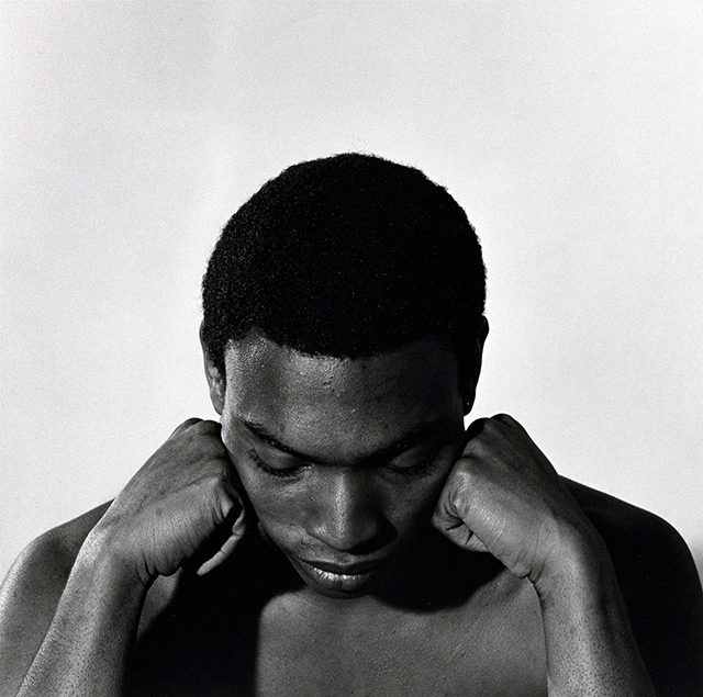 robert MAPPLETHORPE foto in bianco e nero di primo piano ragazzo africano a torso nudo con i pugni appoggiati sul viso e lo sguardo basso