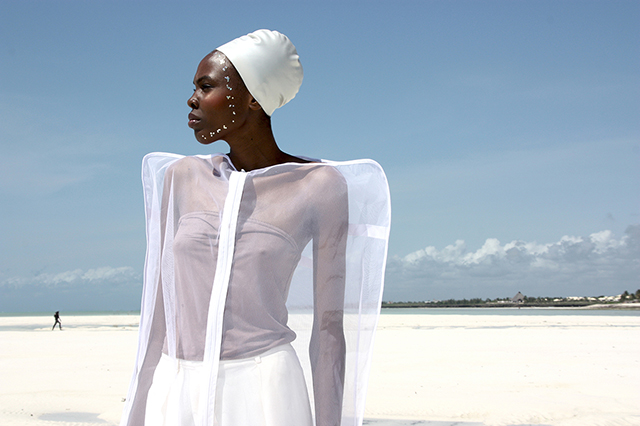 sant'era e sabrina poli santafrika modella africana con copricapo bianco e camicia bianca trasparente su spiaggia bianca con in fondo il mare