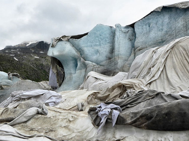 beba stoppani 0° a 5000 mt foto a colori di ghiacciaio di colore azzurro ricoperto di stracci con sullo sfondo montagne con spruzzate di neve sulla cima e cielo grigio nuvoloso