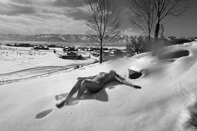 Letizia Battaglia Corpo di donna 2022 foto in bianco e nero di donna nuda sdraiata sulla neve con le braccia aperte davanti a paesaggio innevato