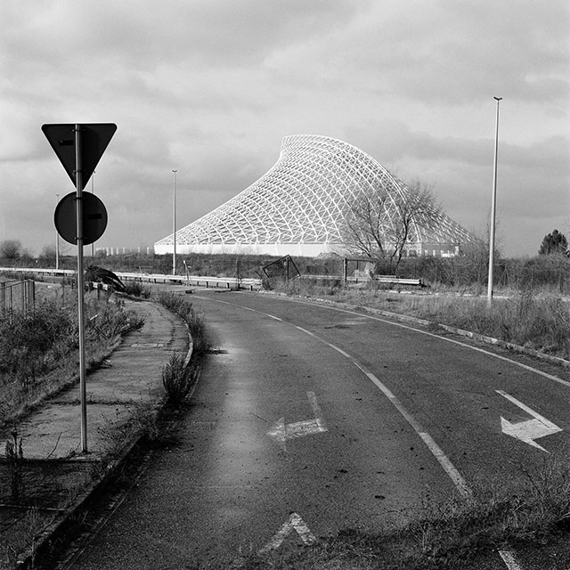 Manuel Cicchetti Tempo intermedio foto in bianco e nero di strada abbandonata alla periferia di Roma con sullo sfondo la costruzione bianca a forma di vela dell'architetto Calatrava