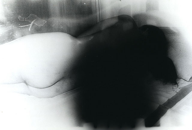 Oliver Pin-Fat foto in bianco e nero molto mossa di donna nuda sdraiata di spalle con folti capelli neri