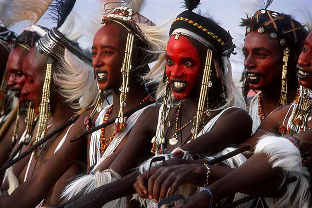 Foggia fotografia primo piano di donne africane con trucchi arancioni sulla faccia e copricapi di piume ballano con volti sorridenti