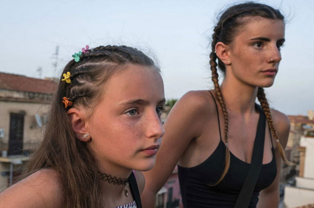 Riccardo Venturi stati d'infanzia Viaggi nel paese che cresce primo piano di due ragazze vestite estive con i capelli acconciati con tante treccine su una terrazza di Roma che guardano davanti a loro con sguardo serio