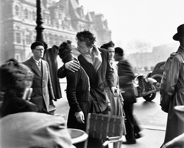 robert doisneau coppia di giovani che si baciano in strada a parigi circondati da passanti