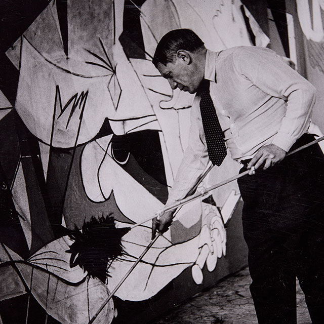 Picasso e Guernica Nuoro foto in bianco e nero dell'artista Picasso che dipinge il quadro Guernica