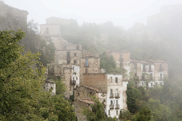 Paesi perduti Trento foto a colori di paese arroccato su una collina immerso nella nebbia