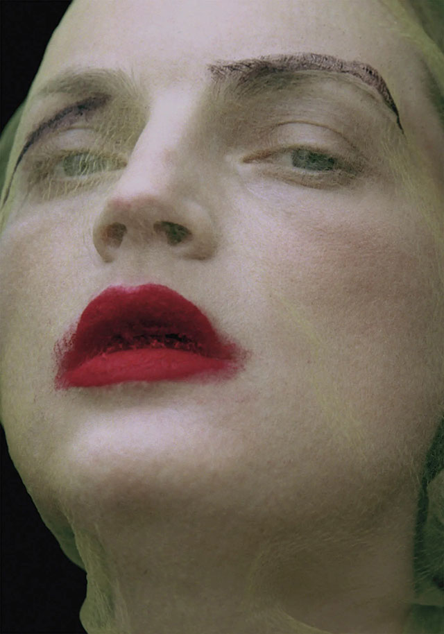 Yelena Yemchuk Milano foto a colori di primo piano di donna con garza sul viso bianco e rossetto rosso sulle labbra