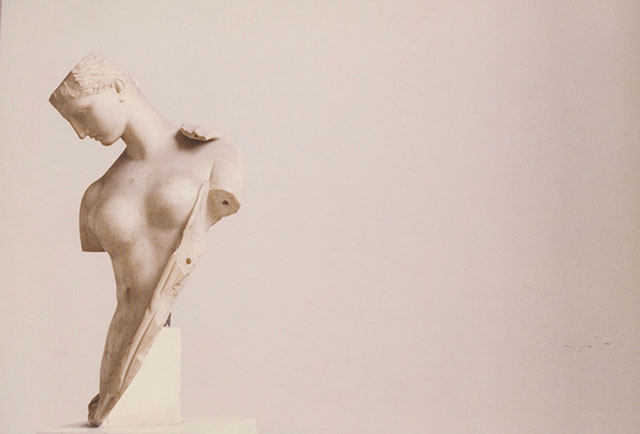 Luigi Ghirri Parma foto a colori di busto di marmo di donna nuda senza le braccia con la testa reclinata su sfondo chiaro