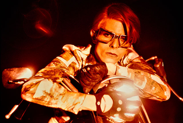 steve shapiro torino foto a colori del cantante david Bowie seduto su una moto con occhiali quadrati e una mano con guanto sul fanale