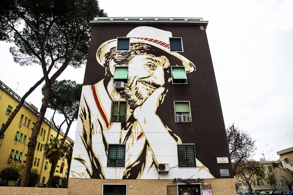 Lazio.Una regione in più per le periferie Roma foto a colori di palazzo nel quartiere Tufello con murales di Gigi Proietti